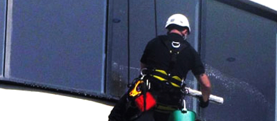 Super Clean South's operative suspended in a harness cleaning windows on a high rise building using a rope access method.